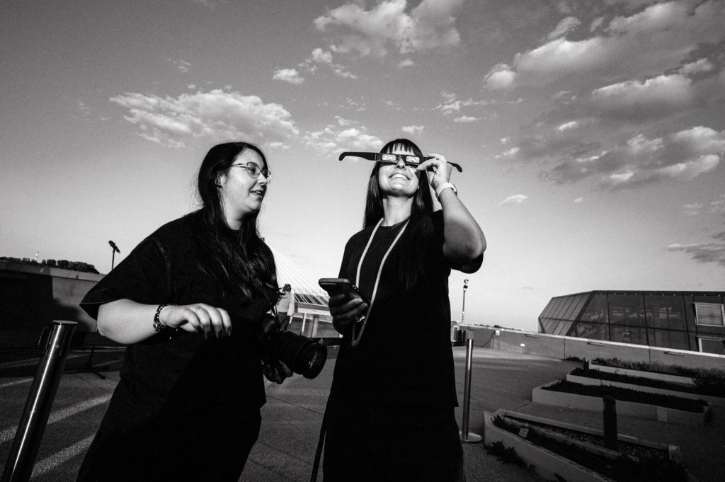 Observers wearing plastic filtered glasses views the partial eclipse