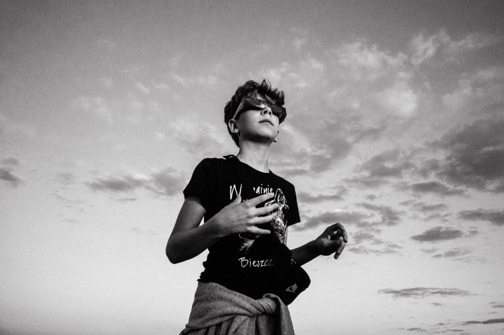 A young boy wearing plastic filtered glasses views the solar eclipse